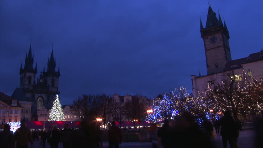 Sunset with walking people on Old Town Square with St. Teyn gothic cathedral in Prague during Christmas market. Time lapse