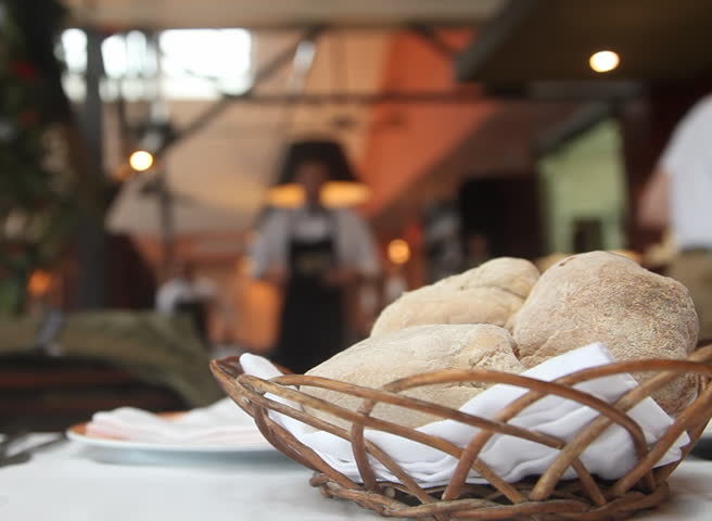 Table setting in restaurant with bread, empty glass and waiters 