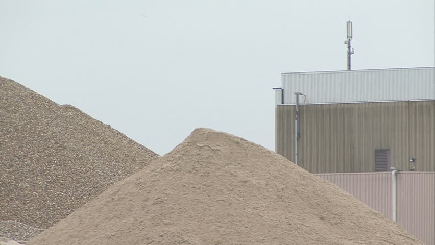 industrial shovel shoves sand on a big pile