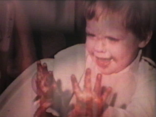 A little girl gets food all over her face while eating dinner as her family members look on.