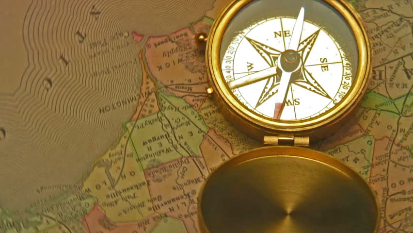 Old brass compass over antique map spinning around