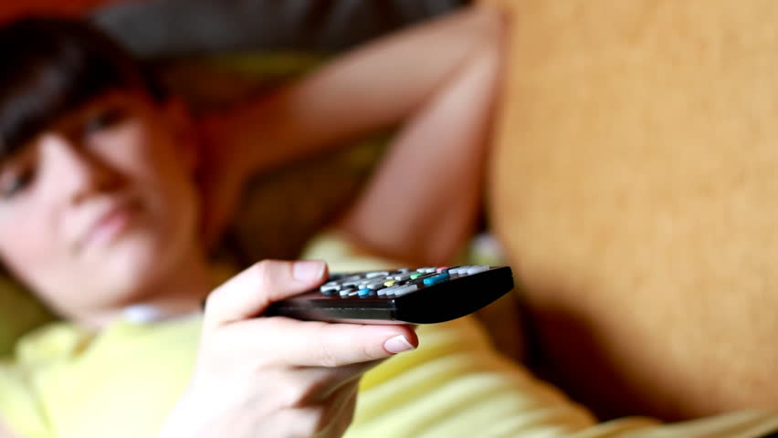 Dolly shot of Woman on a sofa with a tv remote control  - 1080p