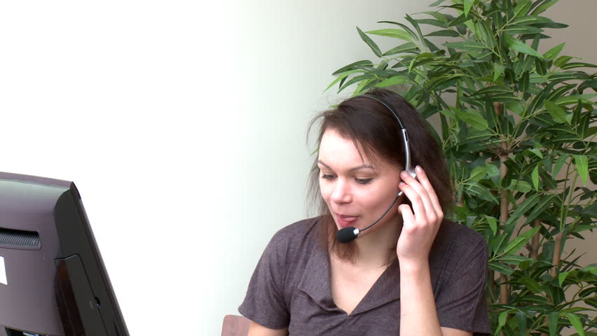 Jolly woman with headset on working at a computer at home