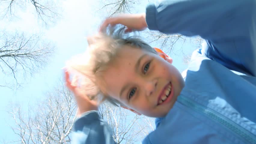 boy and little girl looks top-down and pokes fingers to camera against sky 