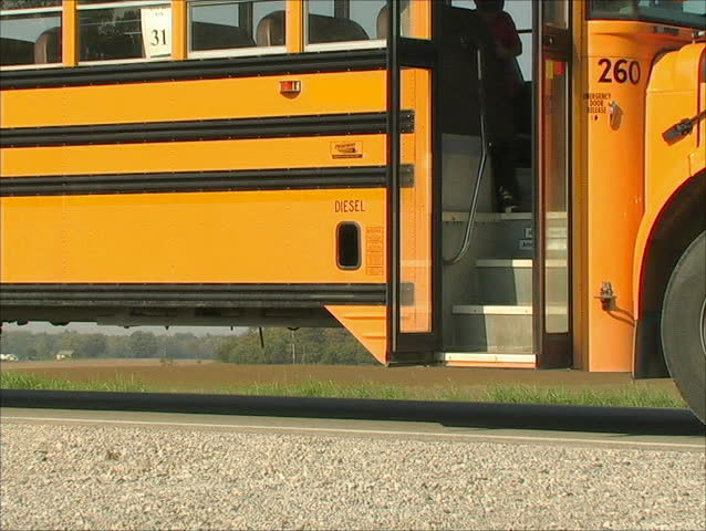 A YOUNG STUDENT JUMPS OFF THE SCHOOL BUS AFTER A LONG RIDE HOME.