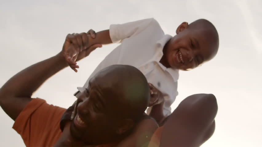 A father and son play in a wheat field on a sunny day.
