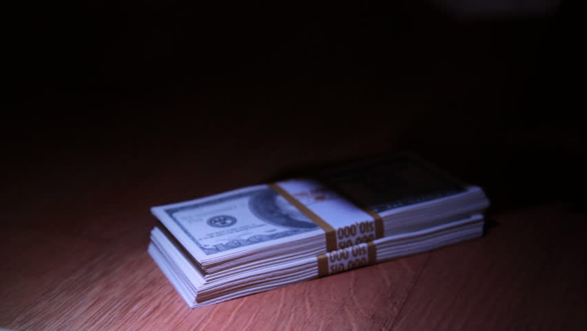 Hand of a criminal puts stacks of dollars