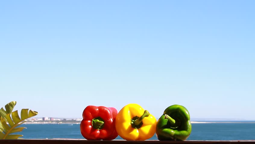 Three colorful chillies peppers and the ocean view