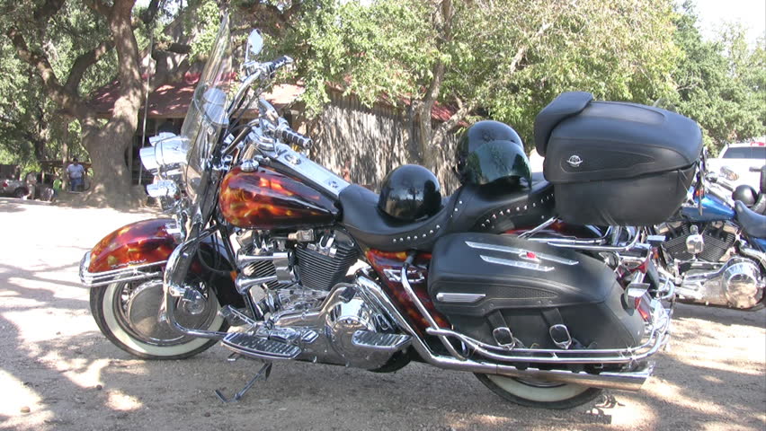 Video of a custom painted motorcycle at Luckenbach Texas. Large group of motorcycle riders with Harley Davidson. Large oak trees and small country store and environment. 