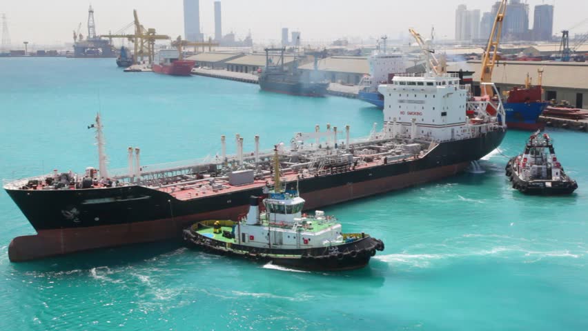 two towing boats turning tanker in sea port