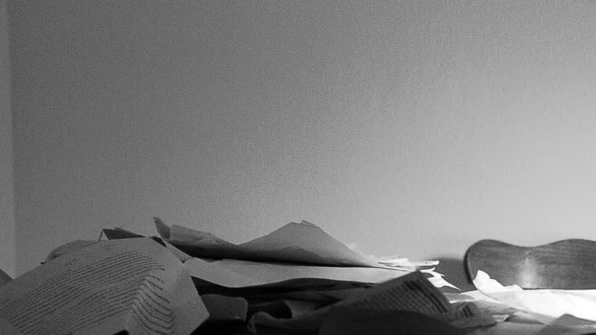 A young man frantically trying to do an overwhelming amount of paper work. Black and white HD 720p footage.