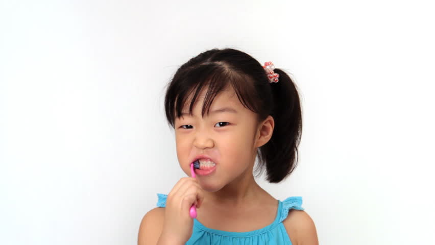 Little girl looks at camera and brushes her teeth