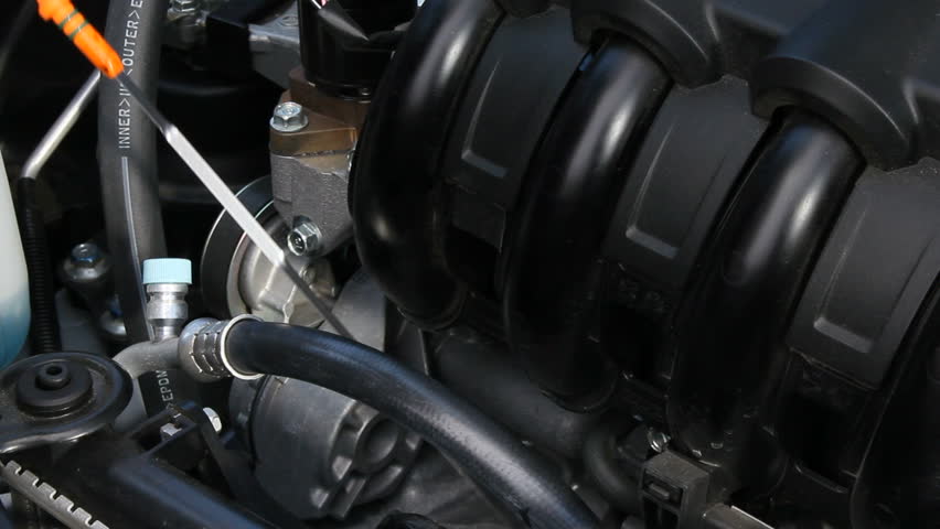 A mechanic checks the level of oil in a new hybrid vehicle