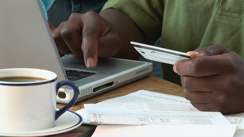Young African American couple using credit card on laptop
