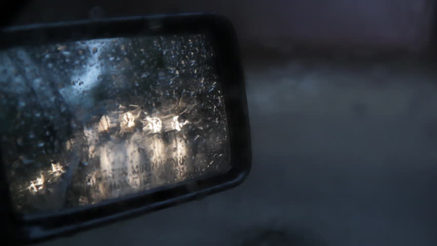 Side mirror with sound of rain. View of headlights in side mirror on rainy day. Good audio. 