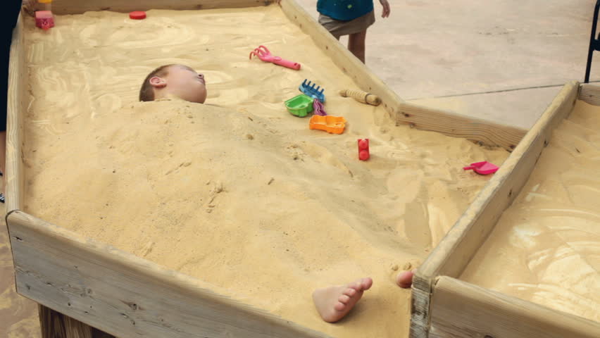 Boy buried in sand getting up
