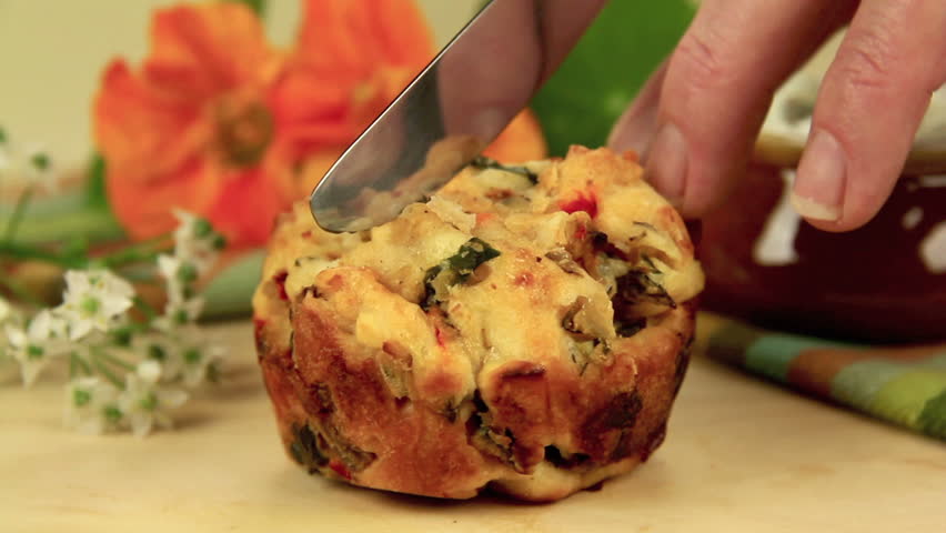 Fresh baked savory muffin cut in half then buttered with herb spread and sprinkled with parsley.
