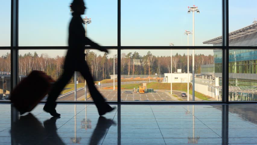 silhouettes of family hurry to aircraft against window at airport