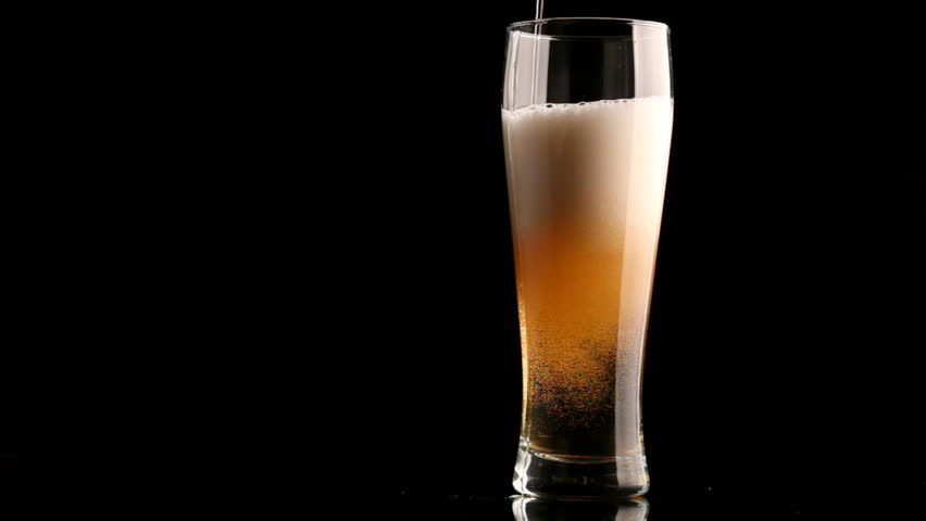 Beer poured in glass on black background