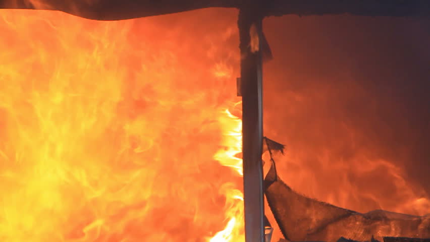 Fire fast motion and intense house burning with flames and smoke coming through broken window.