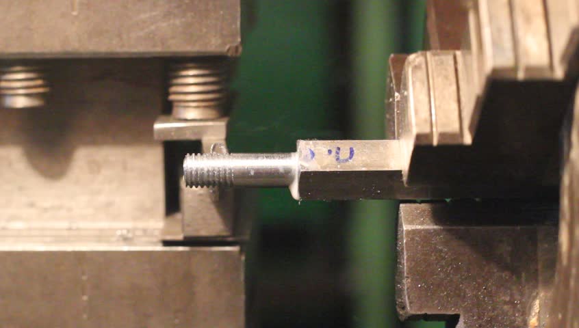 Industrial worker makes a stud using a lathe machine 