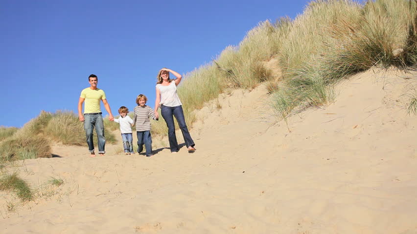 Attractive young caucasian family enjoying vacation time together on coastal sand dunes