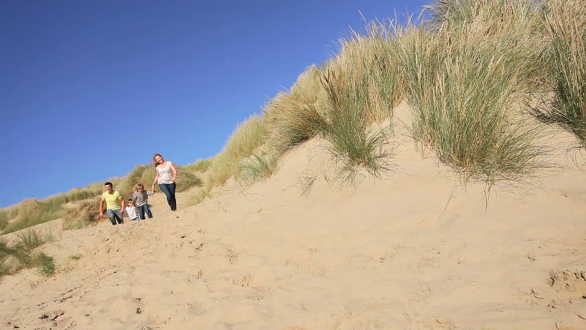 Attractive young caucasian family enjoying vacation time together on coastal sand dunes