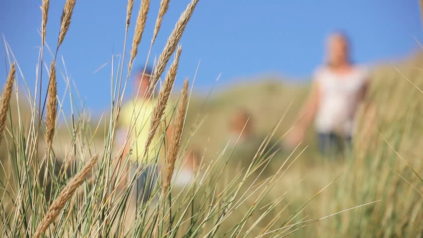 Attractive young caucasian family enjoying vacation time together on coastal sand dunes