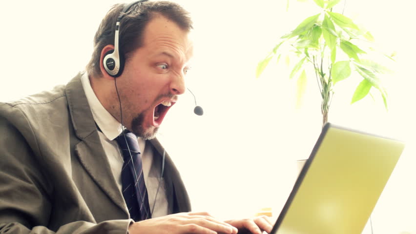 Angry man with headphones screaming at laptop 