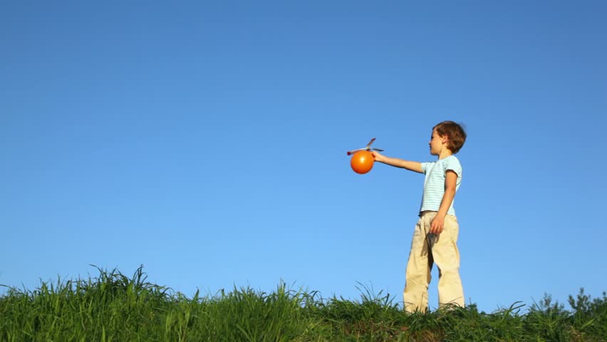 boy launching ball with air-screw and catching it against blue sky