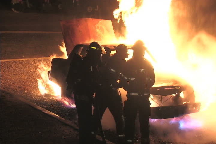Firefighter battle a car fire at night