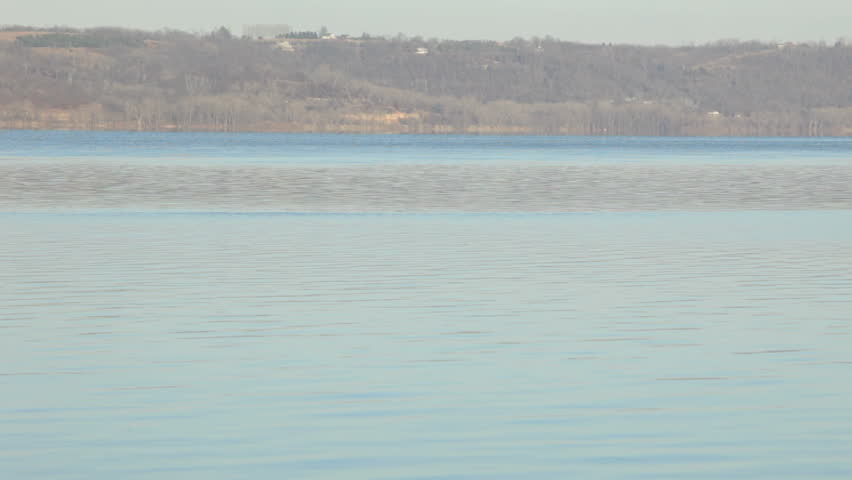 Serene shot of scenic Lake Pepin in Minnesota. Camera tilts up from the beach across the full lake.