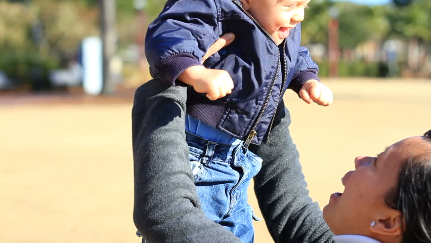 Mother Playing with Baby Son throwing him up in the air.