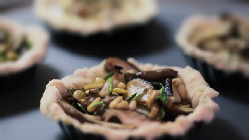 Savory pastry crust with fresh mushrooms and pine nuts being filled with eggs to make quiche.  
