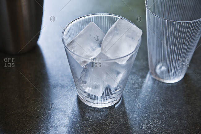 Empty glass with ice cubes and drink shaker.