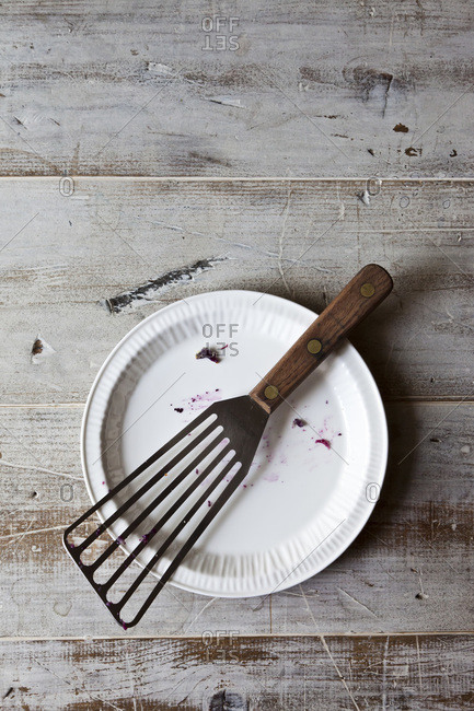 An empty plate with a serving utensil on a wood table