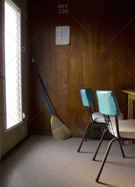 Motel room with broom in corner and two aqua and white vintage chairs
