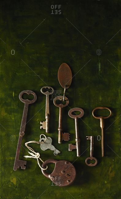 Collection of old vintage keys and lock on crushed green velvet surface