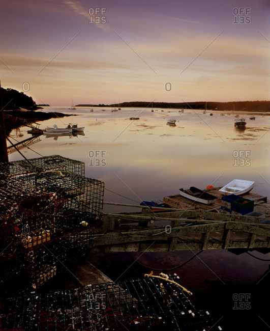 Maine port seen at dawn with fishing boats and lobster pots in foreground