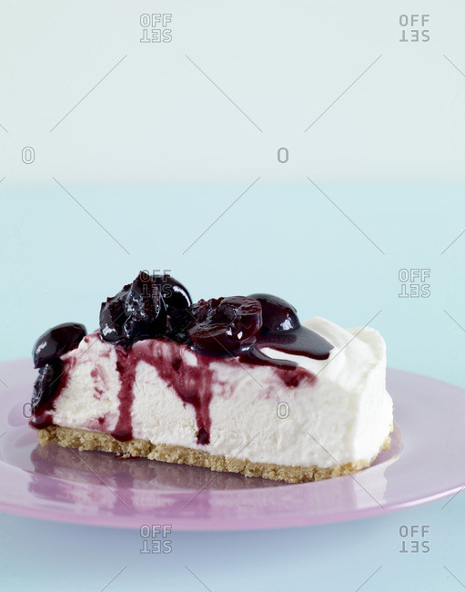 Slice of cheesecake with dripping fruit sauce