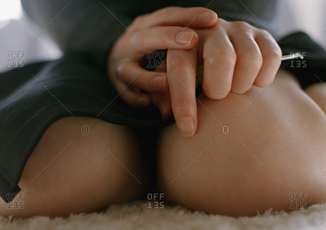 Knees of a woman sitting down with her hands in her lap