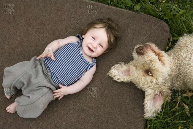 A baby girl and dog lying outside