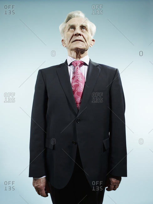 An elegant senior man wearing a suit and pink paisley tie