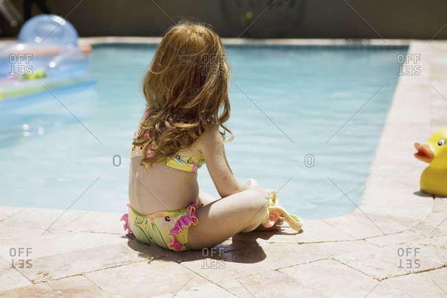Little girl sitting by the pool stock photo