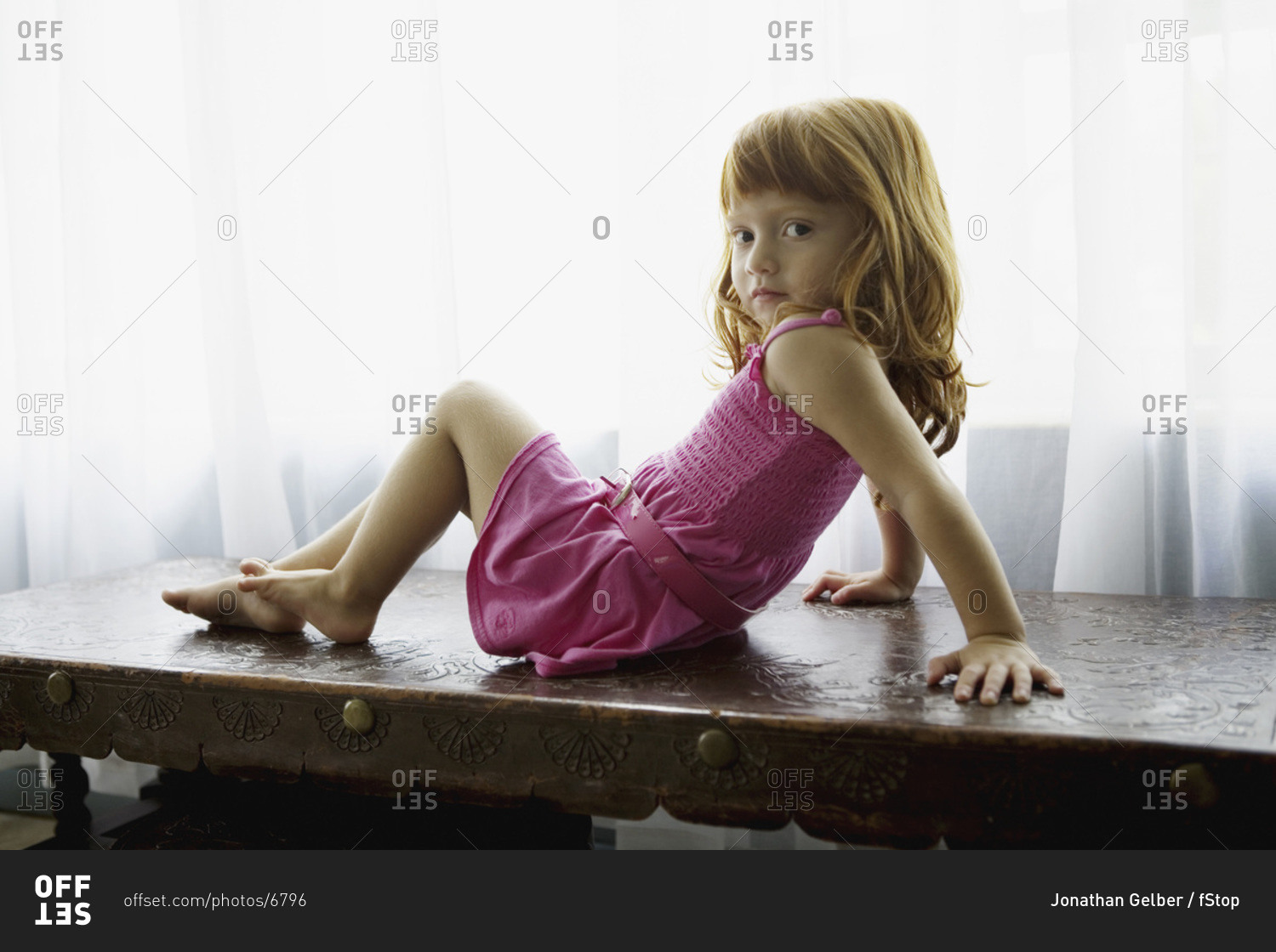Girl sitting on desk posing stock photo - OFFSET