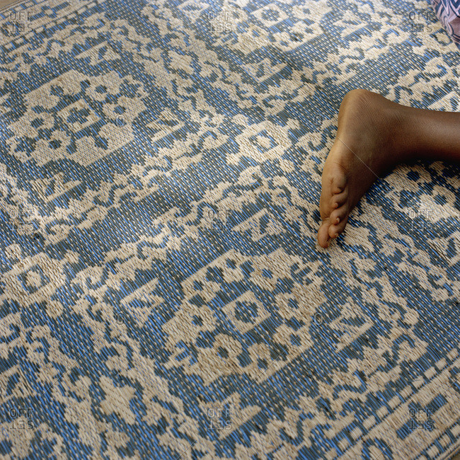 Detail of a person's foot on an patterned rug