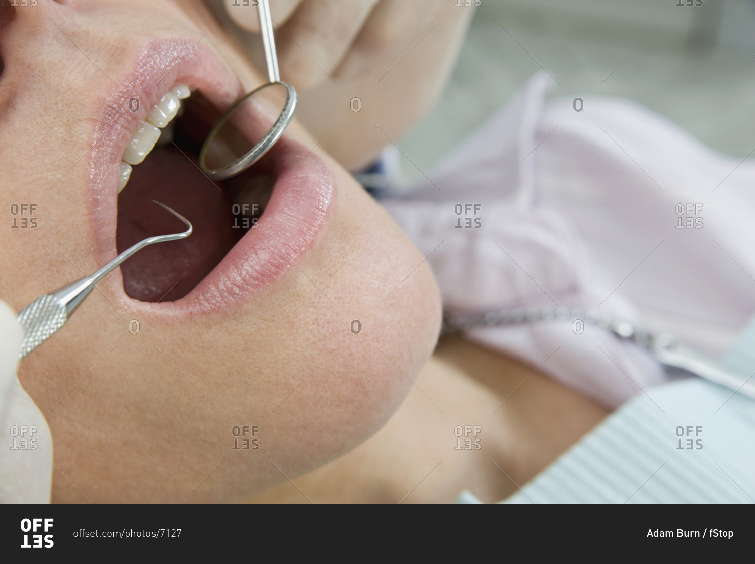 Close-up of a dentist inspecting a woman's mouth