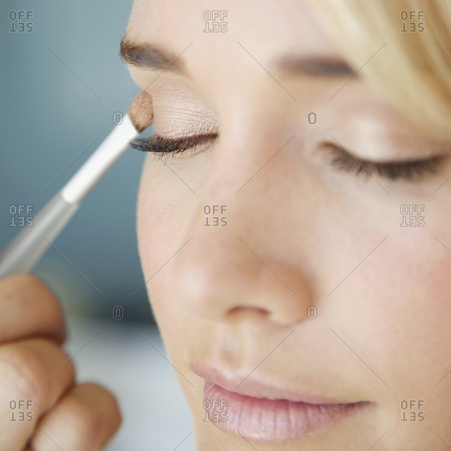 Detail of a young woman applying eye shadow