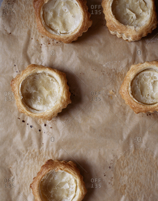Five empty puff pastry on parchment from above