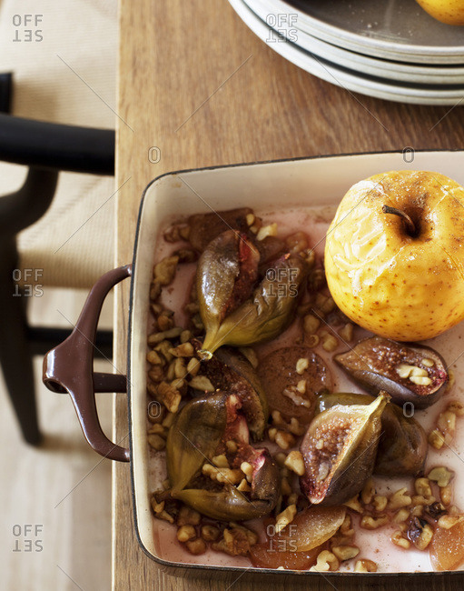 Roasted figs and apple in a roasting pan from above.